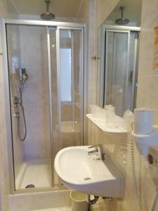 a white bathroom with a shower and a sink at Isenburger Hof in Neu Isenburg