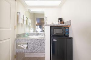 a small bathroom with a black refrigerator and a sink at Turlock Inn in Turlock