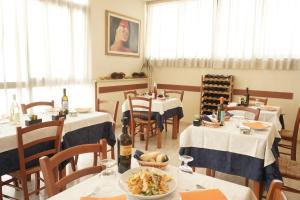 une salle à manger avec des tables, des chaises et une assiette de nourriture dans l'établissement Hotel Caribe, à Viareggio