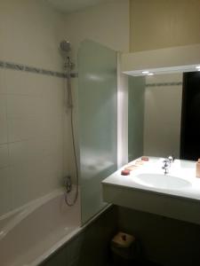a bathroom with a sink and a tub and a mirror at Hôtel La Vanoise in Tignes