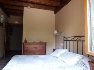 1 dormitorio con 1 cama, vestidor y ventana en La Casuca del Esbardu Hotel, en Vilde