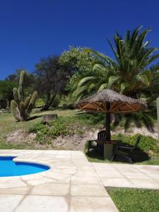 een parasol en een bank naast een zwembad bij posada cerro los nogales in San Agustín de Valle Fértil