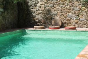 a swimming pool with straw hats next to a stone wall at Casa Migdia in Sant Jordi Desvalls