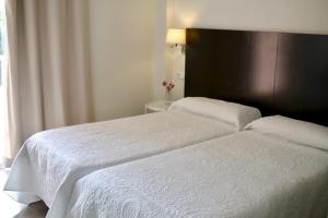 two beds in a hotel room with white sheets at Hostal Jakiton in Palmanova