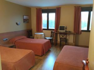 a hotel room with two beds and a desk at Hotel Don Pepe Lago de Sanabria in Ribadelago
