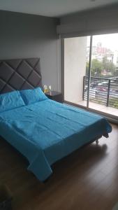 1 cama azul en un dormitorio con ventana grande en Division del Norte Rooms, en Ciudad de México