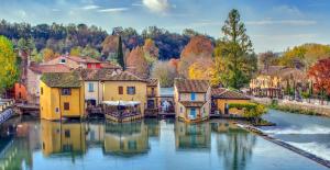 un pueblo en el agua con árboles coloridos en Il Borghetto Vacanze nei Mulini, en Valeggio sul Mincio