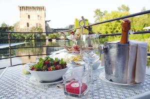 a table with food and a bottle of wine and a salad at Il Borghetto Vacanze nei Mulini in Valeggio sul Mincio