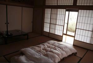 a bedroom with a bed in a room with windows at 富谷緑水庵茶道体験 in Nanakita