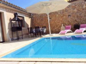 a swimming pool with pink chairs and an umbrella at Casa las Vias in Petra