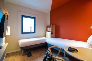 a room with a bed, a desk and a window at ibis budget Rotterdam The Hague Airport in Rotterdam