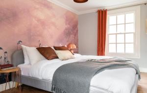 a bedroom with a large bed with a pink wall at The Historic Gem - Central 3BDR Maisonette in Oxford