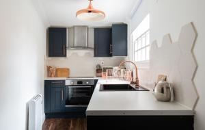 a kitchen with black cabinets and a sink at The Historic Gem - Central 3BDR Maisonette in Oxford