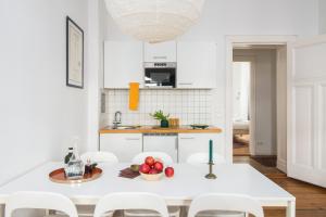 a white kitchen with a white table and chairs at elPilar Friedrichshain in Berlin