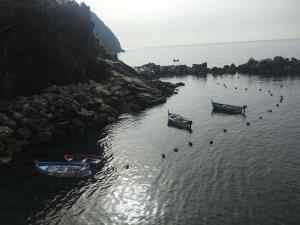 three boats in the water next to a rocky shore at Casa D'amore in Riomaggiore