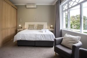 een slaapkamer met een bed, een stoel en een raam bij Summerwood Guest House in Stellenbosch