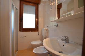 un bagno con lavandino, WC e finestra di Appartamenti Angela e Pordenone a Bibione Altre 25 foto