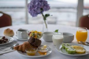 a table topped with plates of breakfast foods and orange juice at Azoris Faial Garden – Resort Hotel in Horta