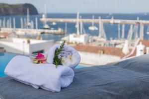 a white towel with flowers and a bowl on a table at Azoris Faial Garden – Resort Hotel in Horta