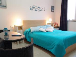 a bedroom with a bed with a blue blanket and a table at Le Onde in Levanto