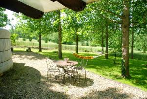 a table and chairs in a yard with a hammock at Yourtes de Gascogne in Lannes