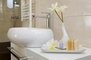 a bathroom sink with a white vase with flowers in it at Hotel Villa Telenta in Vela Luka