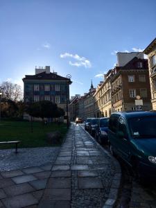 una calle de la ciudad con coches y edificios aparcados en Przytulny apartament przy Barbakanie en Varsovia