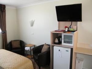 ein Hotelzimmer mit einem Bett, einem TV und einem Stuhl in der Unterkunft Clansman Motel in Glen Innes