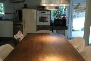 cocina con mesa de madera y sillas blancas en Chambre dans ancienne Ferme rénovée en Éteimbes