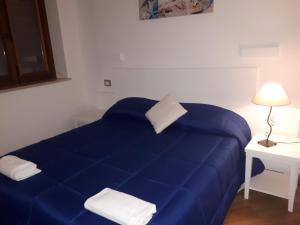 Cama azul en habitación blanca con lámpara en Hotel Il Pirata, en Cinisi