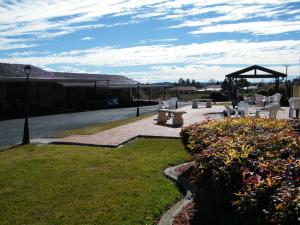 un patio con mesas y sillas y un cenador en Clansman Motel, en Glen Innes