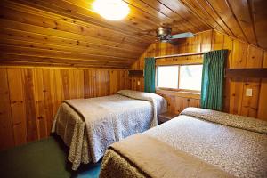 a bedroom with two beds in a wooden cabin at Idlewilde by the River in Estes Park
