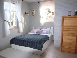 a bedroom with a bed with purple pillows and a window at Dom pod Kogutem in Pasym