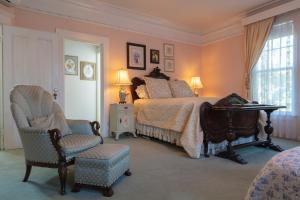 a bedroom with a bed and a chair and a table at The Bissell House Bed & Breakfast in Pasadena