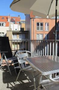 a table and chairs on a balcony with an umbrella at Residentie Lautrec in Knokke-Heist