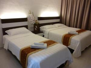 two beds in a hotel room with towels on them at New Century Hotel Melaka in Melaka