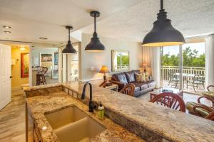 Una cocina con fregadero y una sala de estar. en Sunrise Suites Tahiti Suite #104, en Key West