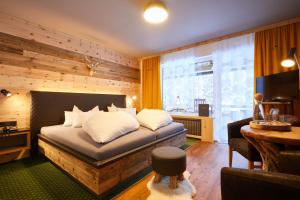 a bedroom with a bed and a television in a room at Boutique Hotel Längenfelder Hof in Grainau
