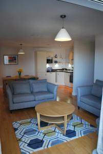 ニューキーにあるFor the Shore, Fistral Beach Newquay - 2 Bed 2 bath - Private Parking with garage for 2 vehiclesのリビングルーム(青いソファ2台、テーブル付)