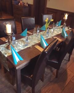 a wooden table with blue napkins and chairs around it at Penzion a Reštaurácia Hanišberg in Krupina