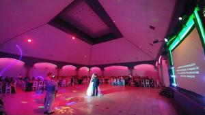 a bride and groom dancing in a room with pink lighting at HOTEL POSADA DEL SOL in Apatzingán de la Constitución