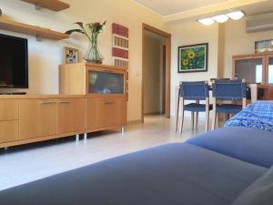 un soggiorno con TV e tavolo con sedie di .Apartamento 1a linea de playa + piscina + parking DAIMUS a Daimuz