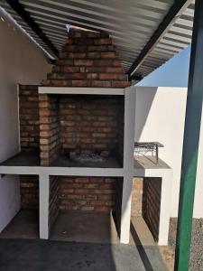 a brick fireplace under a roof with a table at Kalamata in Beaufort West