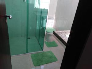 uma casa de banho com um chuveiro e um WC com tapetes verdes em Ótimo apto Praia Bessa em João Pessoa