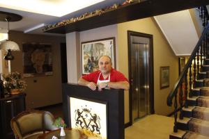 a man standing behind a fireplace in a living room at Hotel Victoria Tirana in Tirana