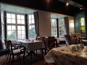 a dining room with tables and chairs and windows at The Chelsea in Llandudno