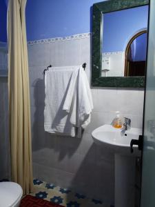 ein Badezimmer mit einem Waschbecken, einem WC und einem Spiegel in der Unterkunft Hôtel Koutoubia in Chefchaouen