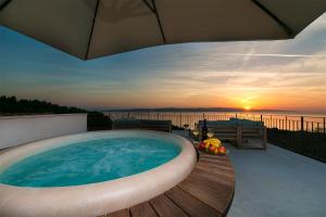 a hot tub on a deck with the sunset in the background at Old Village Brela in Brela