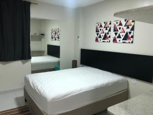 a white bedroom with a bed and a mirror at Apartamento alto padrao in Tamandaré