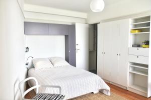 a white bedroom with a bed and a chair at Le Continental in Cayeux-sur-Mer